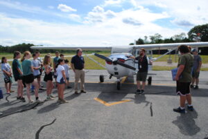 Marshfield Airport Commissioner Patrick MacAlister, center right, and Shoreline Aviation Director of Operations P.J. Flanagan, introduce the visiting Scouts to a Cessna single prop plane.