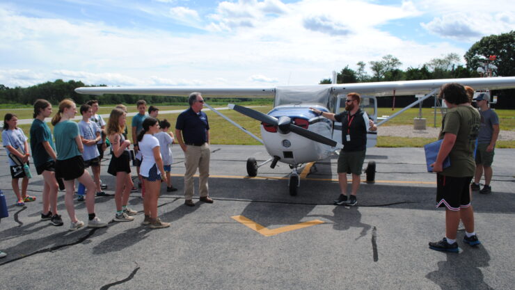 Marshfield Airport Commissioner Patrick MacAlister, center right, and Shoreline Aviation Director of Operations P.J. Flanagan, introduce the visiting Scouts to a Cessna single prop plane.