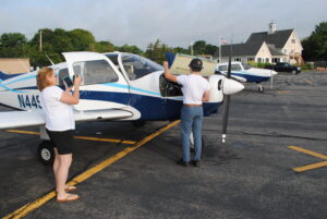 Julie Stiles records her son, Tim, as he check’s the Piper Warrior’s oil level.