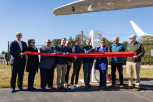Dignitaries cut a ceremonial ribbon celebrating the commissioning of Shoreline Aviation’s new BETA Technologies-designed electric aircraft charging station, at Marshfield Municipal Airport. 