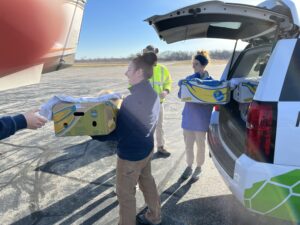 New England Aquarium staff Linda Lory, left, and Emilie Davis transfer rehabbed sea turtles to the plane that will take them to North Carolina. 