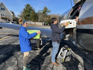 Shoreline Aviation’s Chris Davis and New England Aquarium’s Emilie Davis hand sea turtles to volunteer pilot Steve Bernstein. Photo/Shoreline Aviation