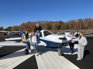 Isabella DiRusso, left, Abby Marinelli, Andrea Hewett, Helen Lin, and Varvara Karenski mug with one of Shoreline Aviation’s Piper Warrior trainer planes.