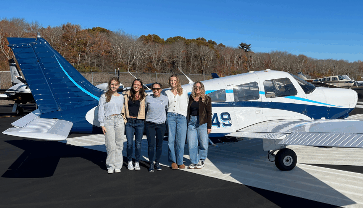 Varvara Karenski, left, Isabella DiRusso, Helen Lin, Abby Marinelli, and Andrea Hewett mug with one of Shoreline Aviation’s Piper Warrior trainer planes.
