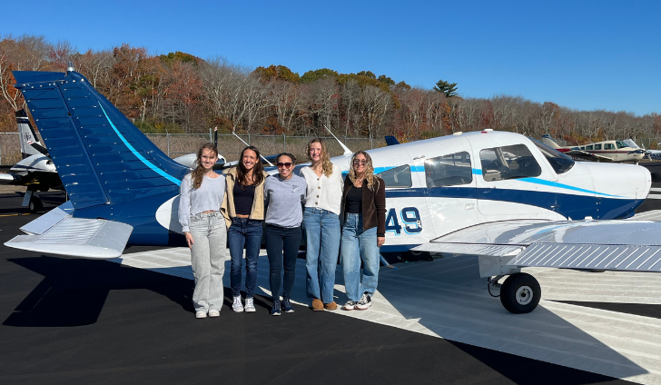 Varvara Karenski, left, Isabella DiRusso, Helen Lin, Abby Marinelli, and Andrea Hewett mug with one of Shoreline Aviation’s Piper Warrior trainer planes.