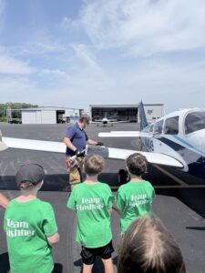 Airport Manager Jason Tibbetts shows visiting second-graders how to fuel an airplane. 